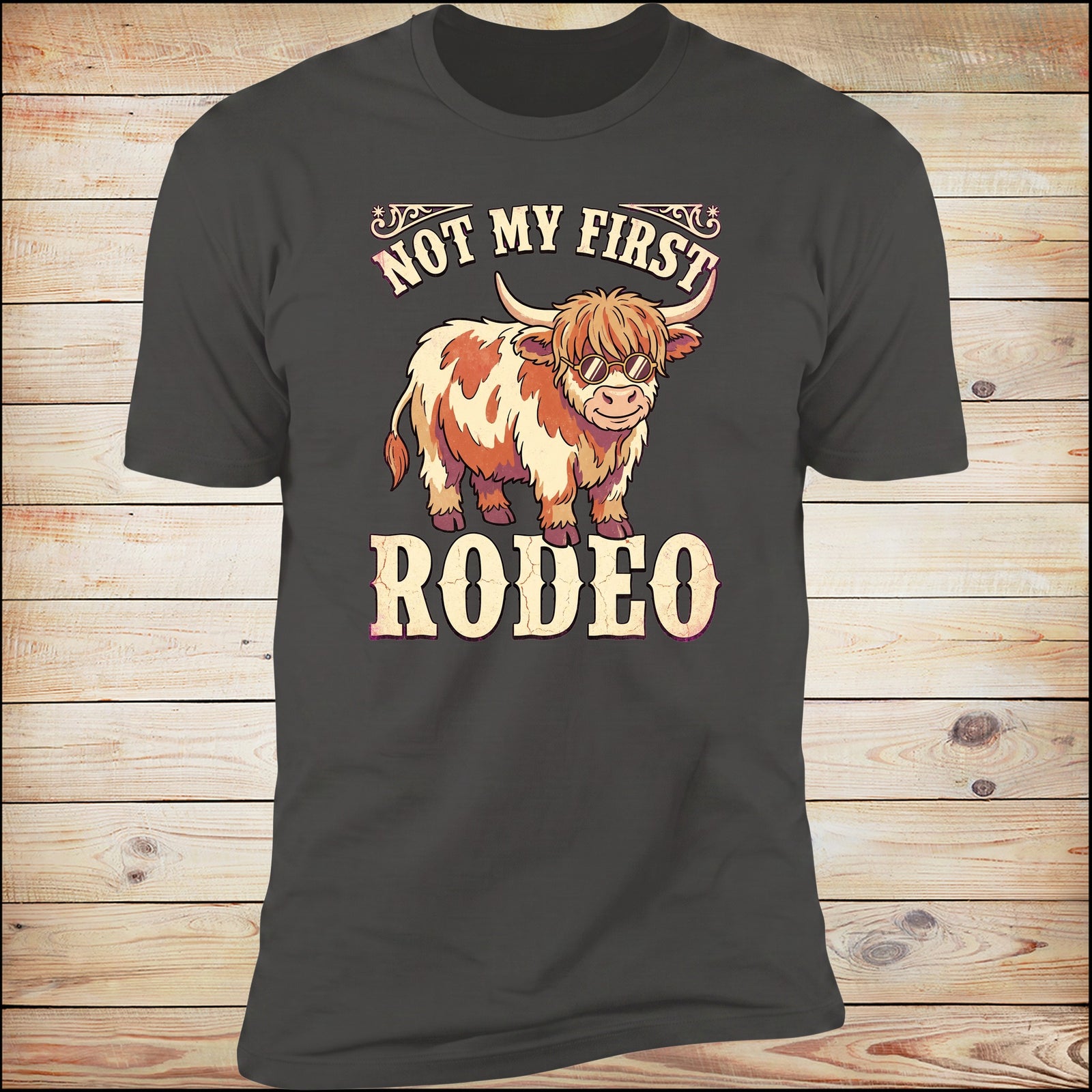 Not My First Rodeo highland cow tee, wood background